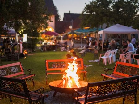 Lagerfeuer mit B&auml;nken und Partyzelten im Garten